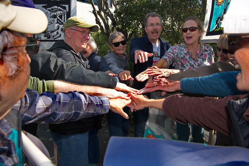 Group of people with their hands together in a circle to kick off a rally